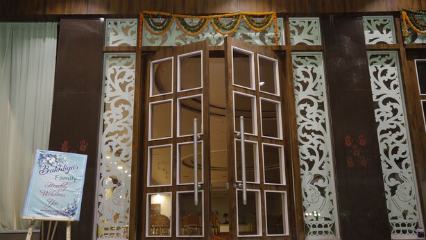 Un edificio tradicional con fachada de madera, un amplio acceso abierto en el centro y paneles decorativos.