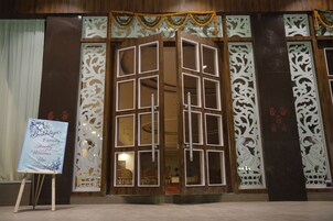 Un edificio tradicional con fachada de madera, un amplio acceso abierto en el centro y paneles decorativos.