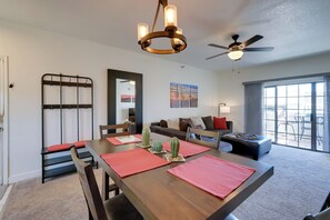 A modern living room with a dining area, a ceiling fan, a chandelier, and a large window with a view. - 1 Mi to Spring Training! Scottsdale Gem w/ Balcony (Scottsdale)