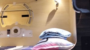 Une chambre compacte et moderne, équipée d’un lit superposé, d’une petite table de chevet et d’un luminaire fixé au mur.