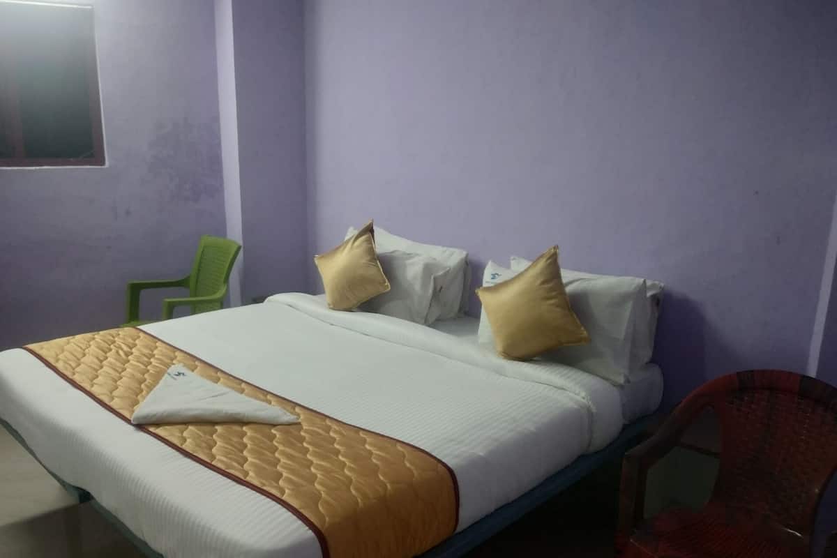 Quarto individual com cama de madeira, roupa de cama branca e dois travesseiros bege.