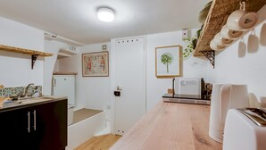 A compact kitchen with a wooden countertop, a white refrigerator, a microwave, and a sink.