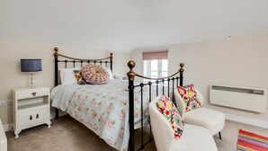 Ein Schlafzimmer mit Bett, Nachttisch, Stuhl und Heizkörper.