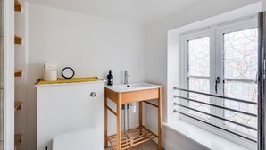 Ein kleines Badezimmer mit Toilette in Weiß, einem Holzlagerflächenstück mit Waschbecken und einem Fenster mit Außenblick.
