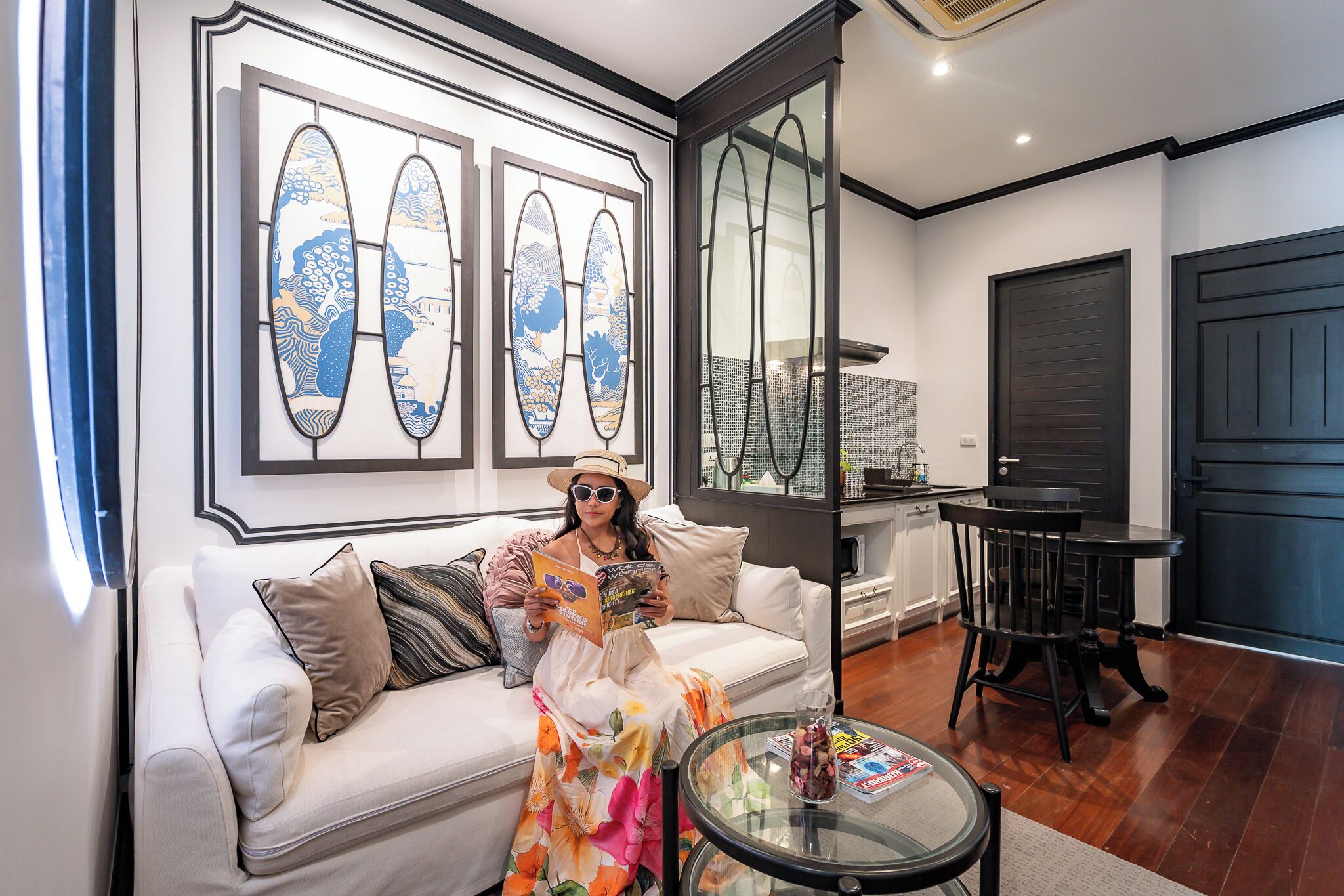 A modern living room with a sofa, a glass coffee table, and a dining area with a chair and table.