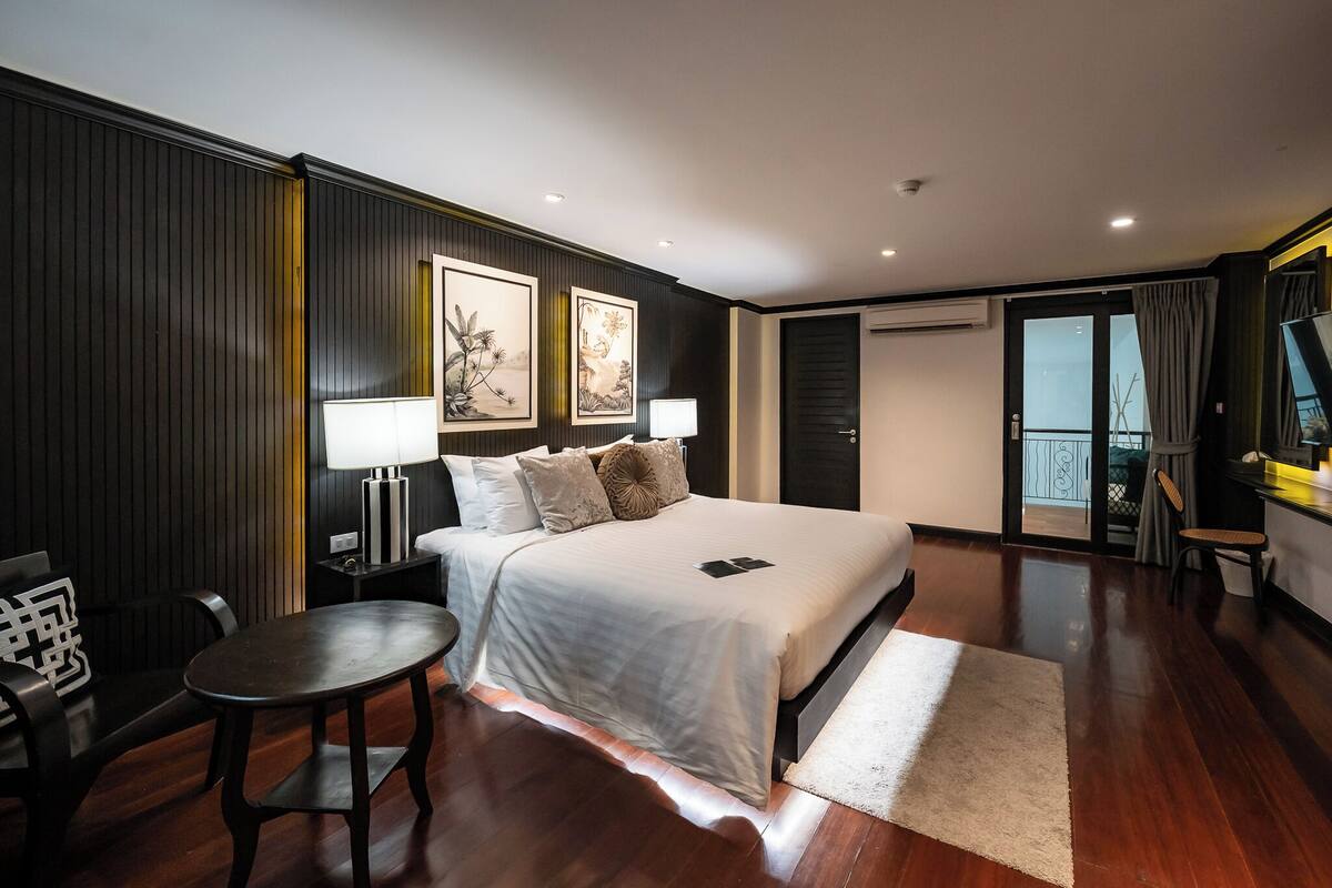 Une chambre d’hôtel comprenant un lit, des tables de chevet, un bureau, une chaise, une télévision et un balcon avec vue.