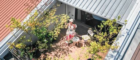 A rooftop patio with a seating area, potted plants, and a person sitting at a table.