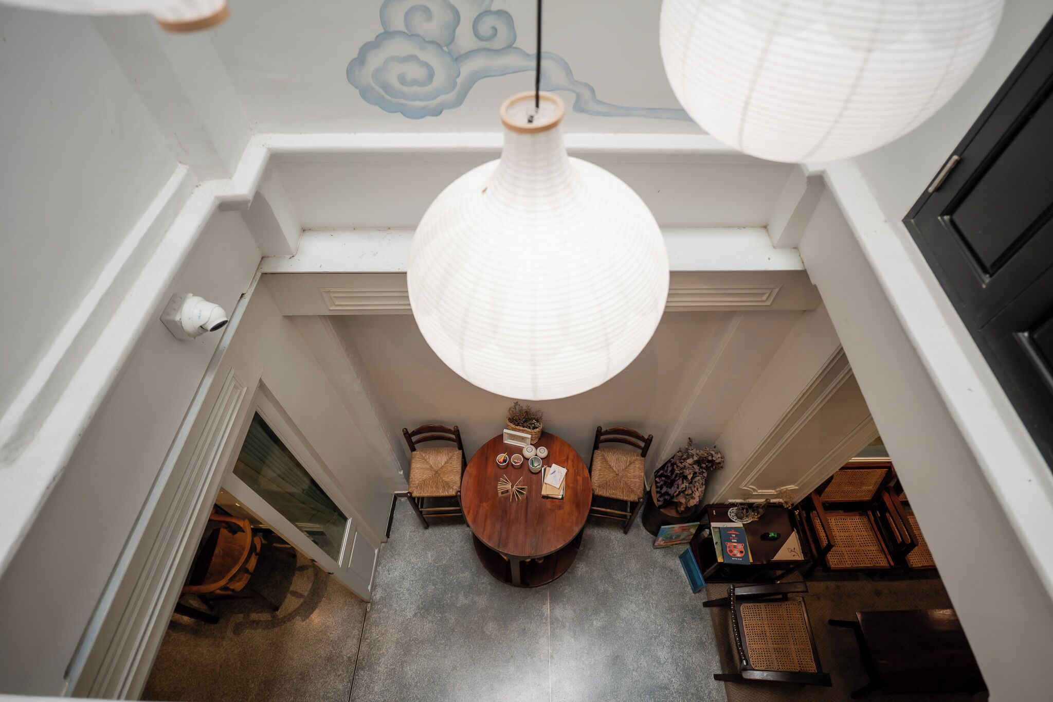 A dining area with a round table, chairs, and hanging paper lanterns.