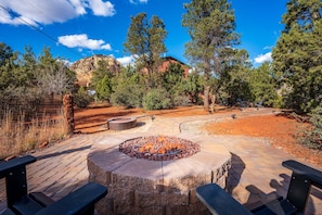 A patio with a stone fire pit, benches, and a view of a mountain.