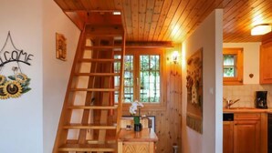 Un escalier en bois mène à une chambre située en mezzanine, qui offre une vue sur l’extérieur.