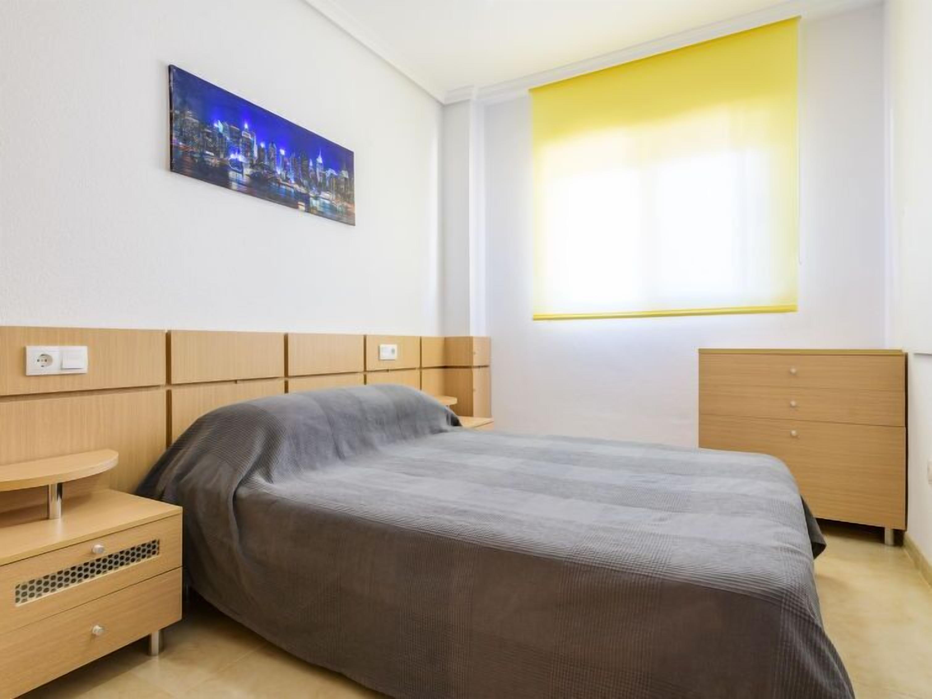 Ein modernes Schlafzimmer mit Bett, Nachttisch und Kommode.