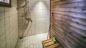A small, tiled shower area with wooden walls and a wooden bench. - Pihatupa 2 by Interhome (Kuusamo)