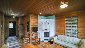 A log cabin interior with a fireplace, wooden furniture, and a patterned wall hanging. - Pihatupa 2 by Interhome (Kuusamo)