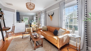 A spacious living room with a leather sofa, wooden coffee table, and a chandelier. - Harvest Moon (Atlanta)