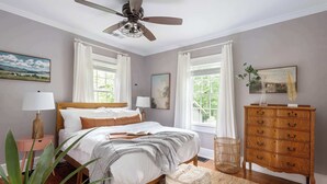 A bedroom with a bed, bedside tables, a dresser, and a ceiling fan. - Harvest Moon (Atlanta)