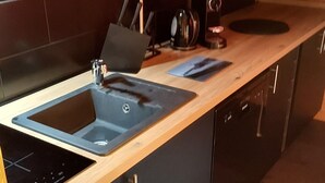 A modern kitchen with a wooden countertop, two sinks, and a built-in oven. - Fully renovated apartment in Valmorel (Les Avanchers-Valmorel)