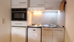 Una cocina compacta equipada con lavavajillas, horno y lavabo.