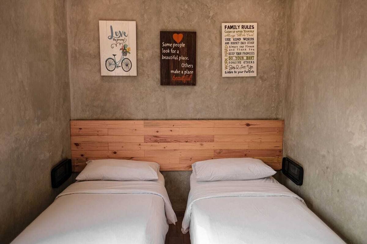 A room with two beds, a wooden headboard, and three wall decorations.