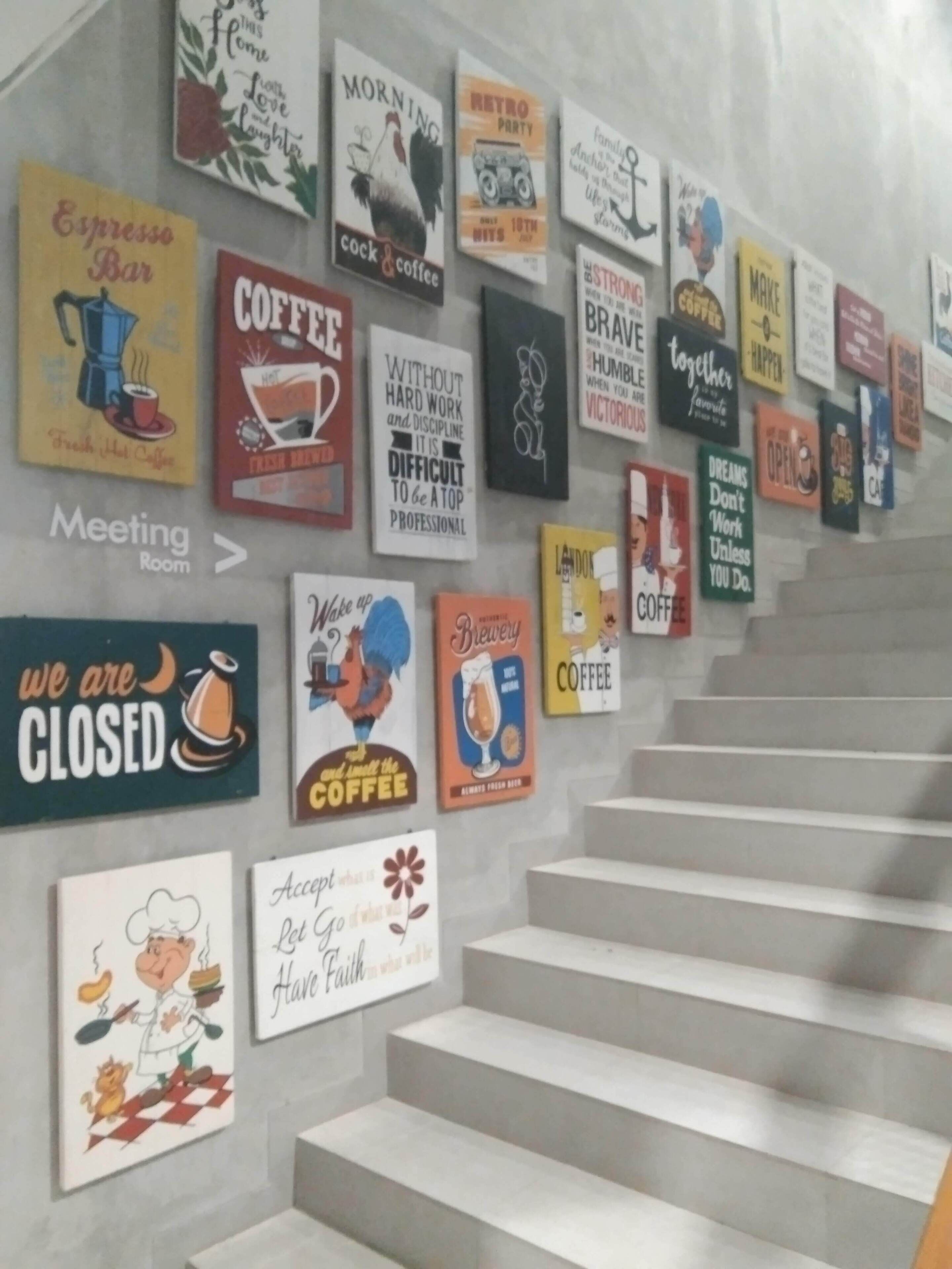 A wall with various coffee-themed posters and signs, including a sign for a meeting room and a sign indicating the coffee shop is closed.