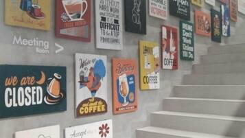 A wall with various coffee-themed posters and signs, including a sign for a meeting room and a sign indicating the coffee shop is closed.