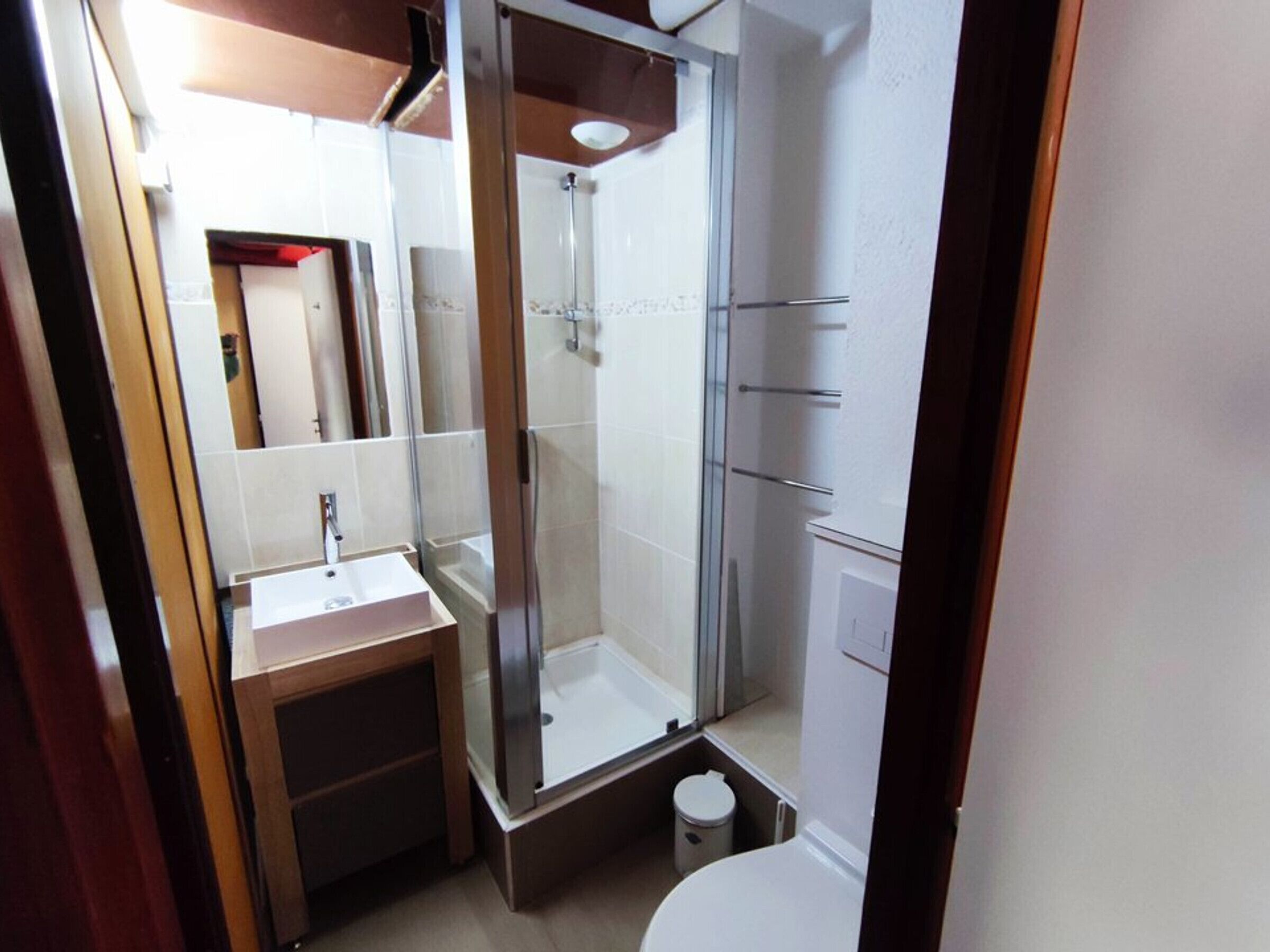 Ein kleines Badezimmer mit Duschkabine, Waschbecken und Toilette.
