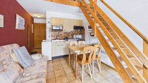 A compact living space with a kitchenette, a dining area, and a staircase.