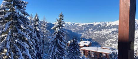 A snow-covered mountain landscape with a lodge featuring a wooden exterior and multiple balconies.