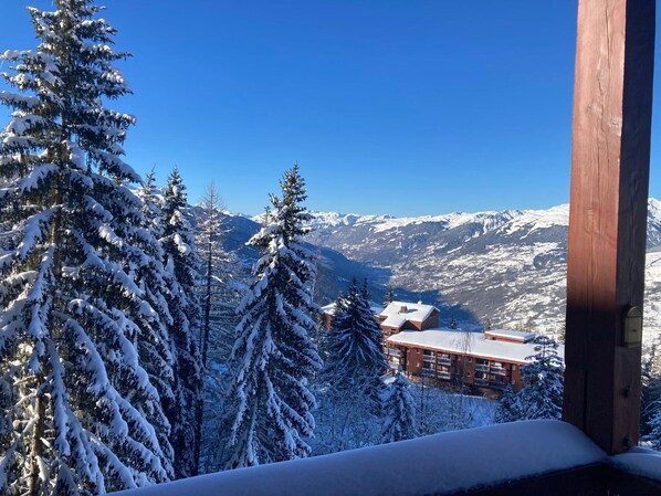 A snow-covered mountain landscape with a lodge featuring a wooden exterior and multiple balconies.