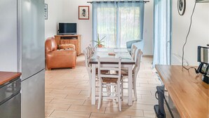A dining area with a wooden table and chairs, a sofa, a television, and a refrigerator. - 3 bedroom stunning home in Trévou-Tréguignec (Trévou-Tréguignec)