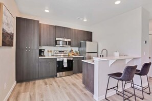 A modern kitchen with dark wood cabinets, stainless steel appliances, and a white countertop.