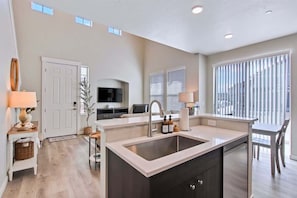 A modern kitchen with a central island, built-in appliances, and a large window providing natural light.