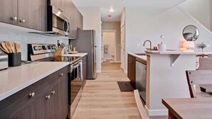 A modern kitchen with dark wood cabinets, stainless steel appliances, and a central island with a sink and mirror.