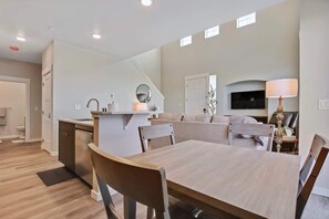 A modern kitchen with a dining area, built-in appliances, and a flat-screen TV.