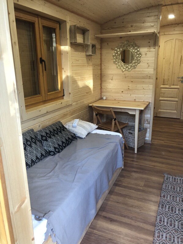 A cozy wooden cabin room with a bed, a desk, and a mirror on the wall. - Riri Travel Trailer (Digoin)