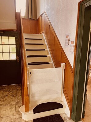 A wooden staircase with a white handrail and a black carpet at the bottom.