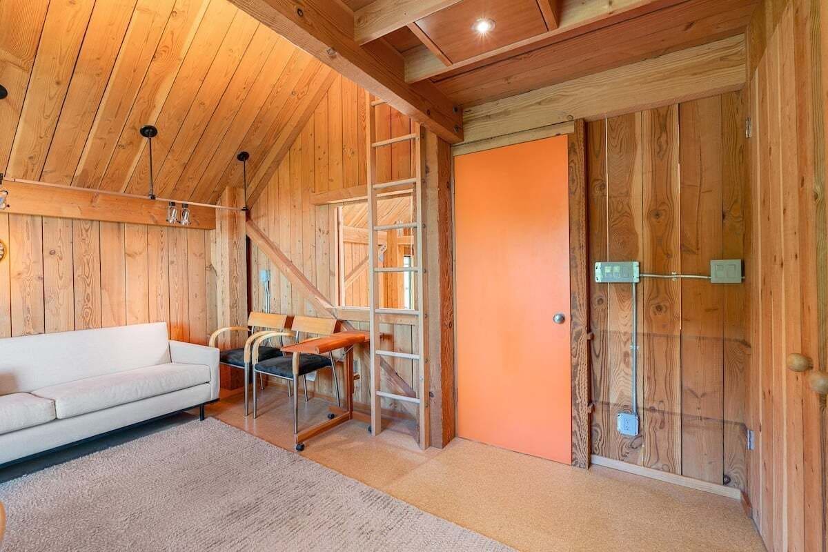 A wooden interior with a sofa, a ladder, and a door.