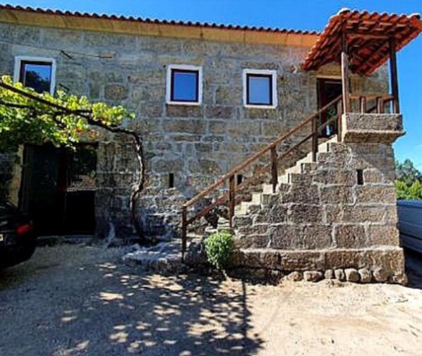 Um edifício de pedra com uma escadaria que leva a um alpendre coberto.