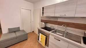 A compact kitchen with a built-in stove, sink, and wooden backsplash.