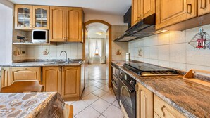 Une cuisine avec des meubles en bois, un four à micro-ondes, une cuisinière et un dosseret carrelé.
