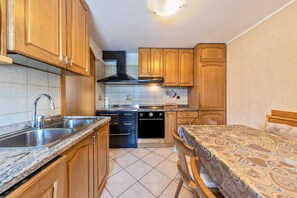 A compact kitchen with wooden cabinets, a stove, and a sink. - Holiday Accommodation "Appartamento Pisani" with Balcony and Wi-Fi (Brez)
