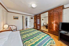 A hotel room with a bed, a television, a wardrobe, and a mirror. - Holiday Accommodation "Appartamento Pisani" with Balcony and Wi-Fi (Brez)