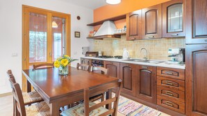 Une cuisine avec des meubles de rangement en bois, une table à manger avec des chaises, une cuisinière et un évier.