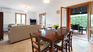 Un coin repas avec une table et des chaises en bois, un canapé et un téléviseur en arrière-plan.