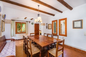 A dining area with a wooden table and chairs, a bench, and a chandelier.