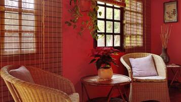 Una habitación con muebles de mimbre, una pared roja y una ventana con vistas.