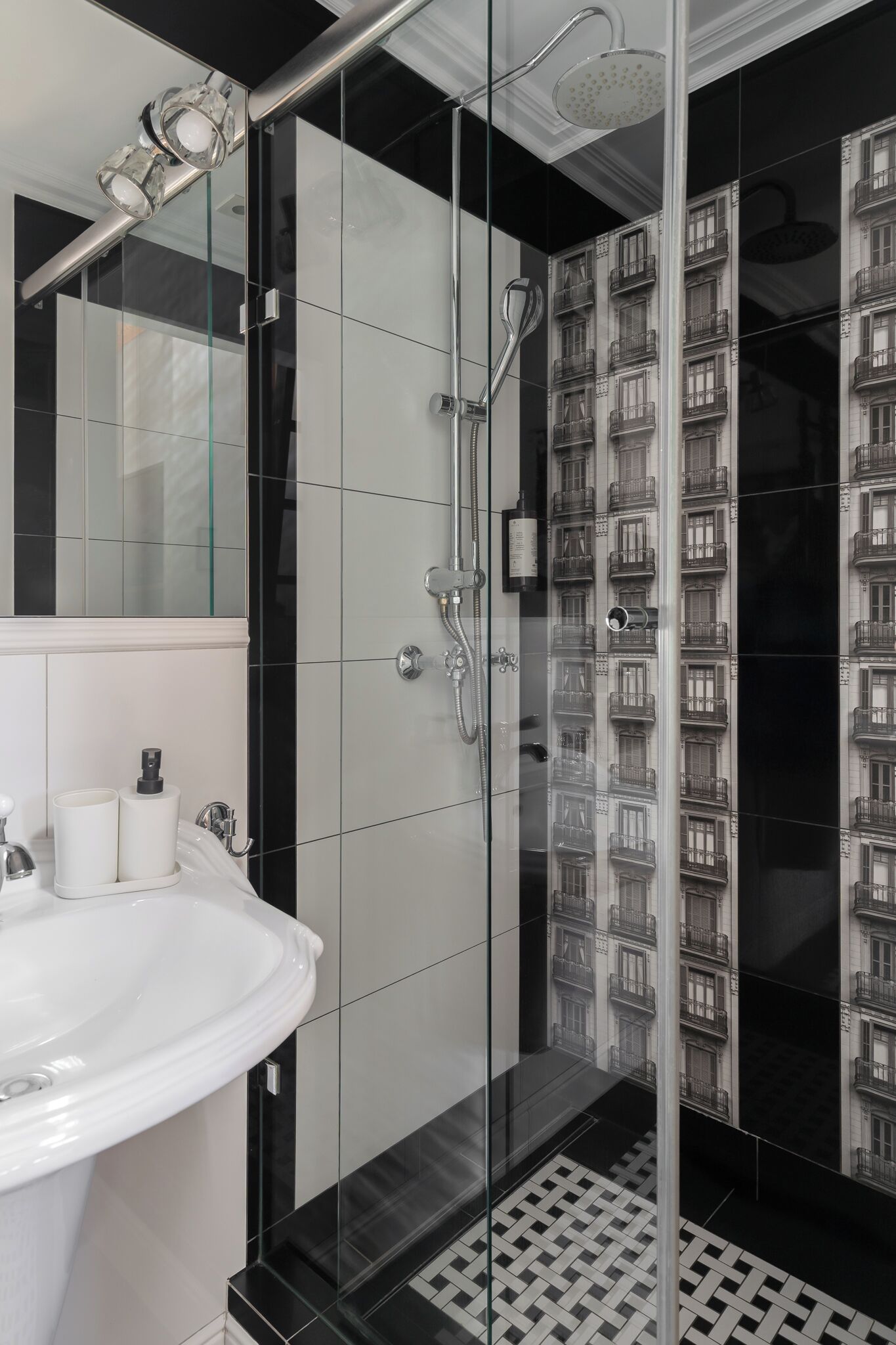A modern bathroom with a glass-enclosed shower, a white sink, and a mirror.
