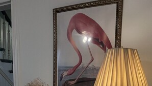 A framed painting of a flamingo, a blue vase with dried flowers, a tissue box, and a lamp on a white dresser. - 17 Cedar - Close to All Star Village in Oneonta, walk to Main St. (Oneonta)