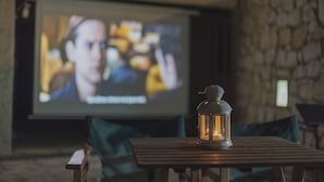 Ett mysigt rum med ett träbord, en lykta och en projektionsduk där en film visas.
