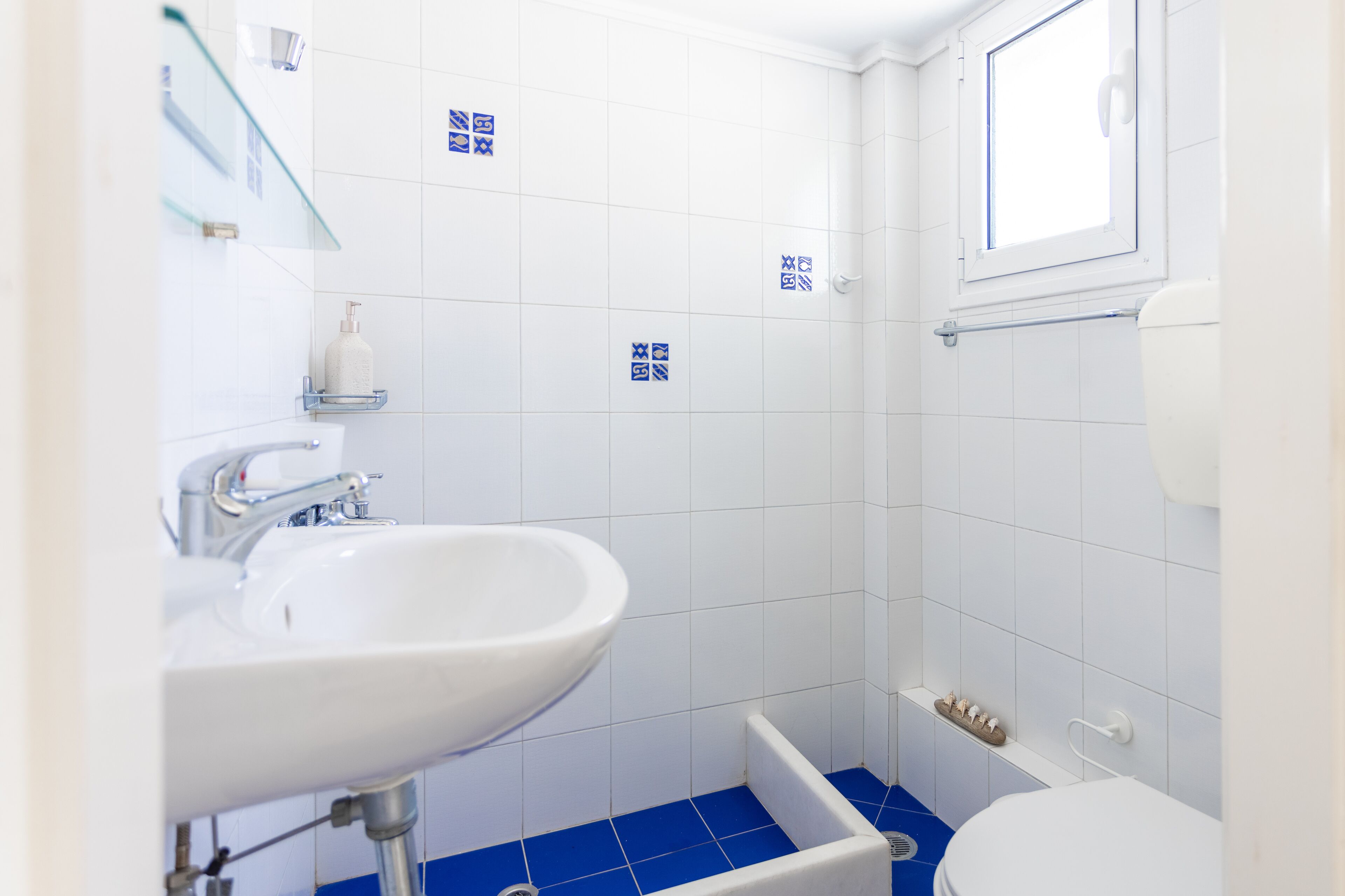 Une petite salle de bain avec un lavabo blanc, des toilettes et un espace douche.