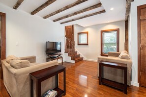 A living room with a wooden staircase, a television, and two sofas.